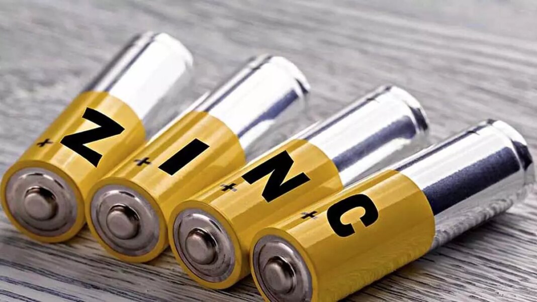 Four AA zinc batteries on wooden surface.