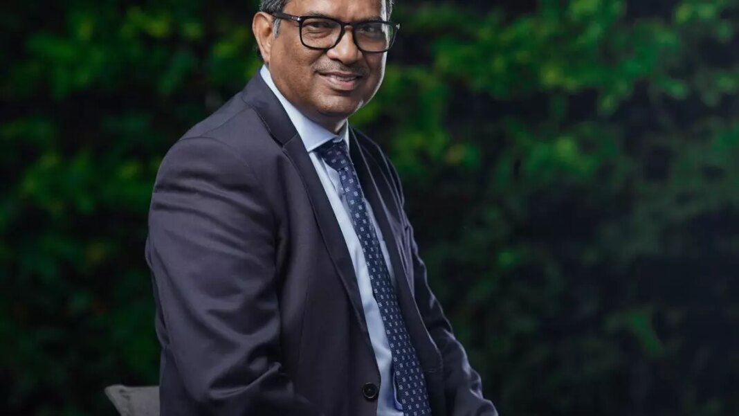 Smiling businessman in suit against green foliage background.