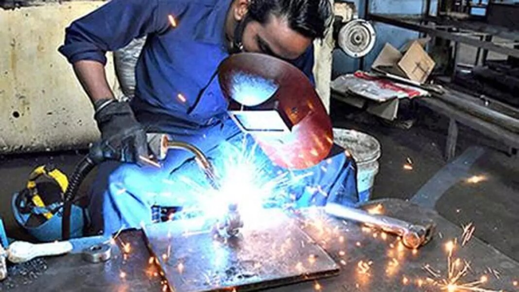 Welder working with sparking equipment in workshop.