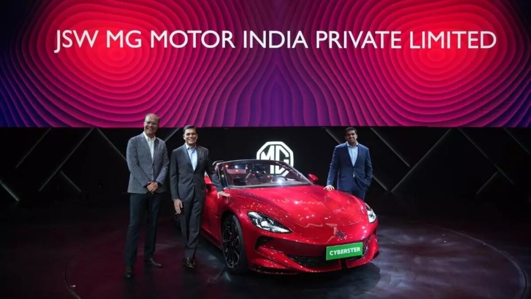 Executives unveiling new red sports car at event.