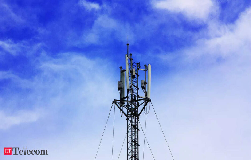 Cellular tower against blue sky with clouds.