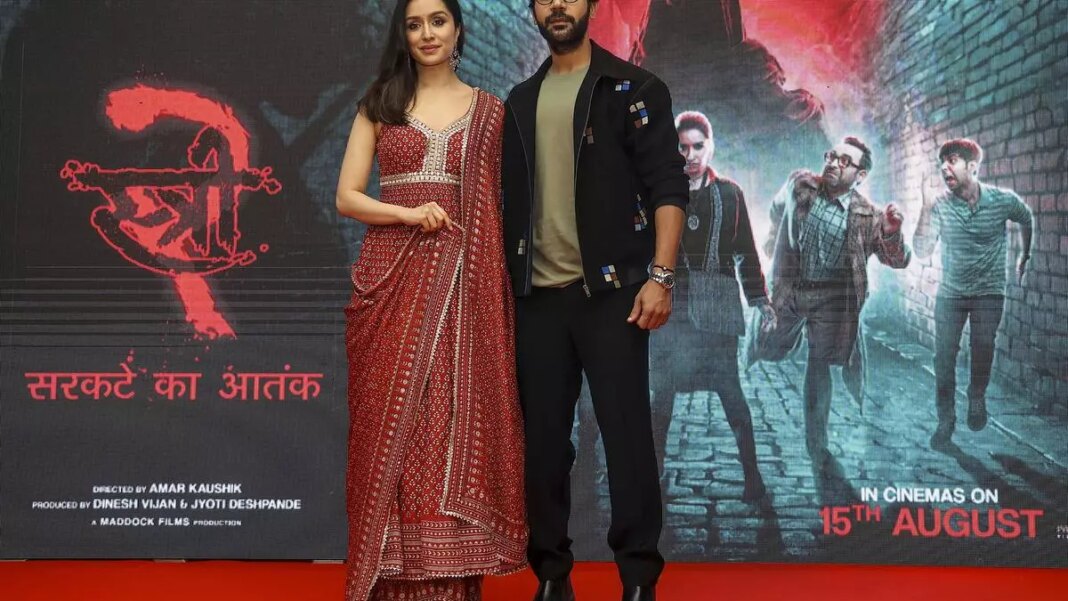 Actors at movie premiere with promotional backdrop.