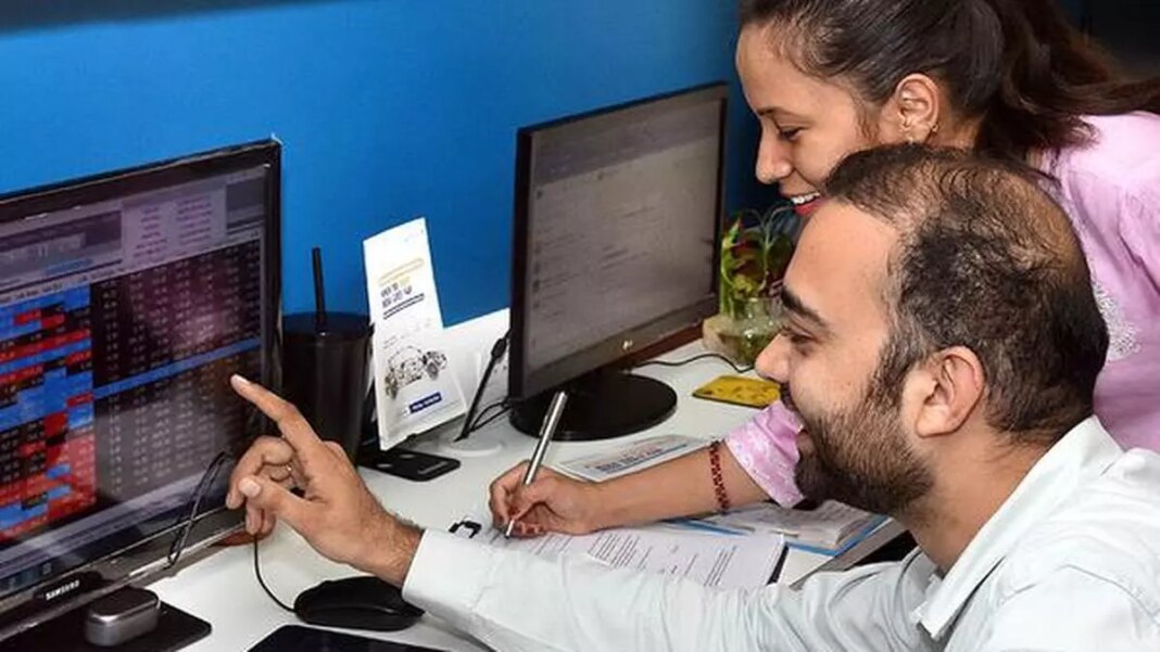 Two colleagues analyzing data on computer screens in office.