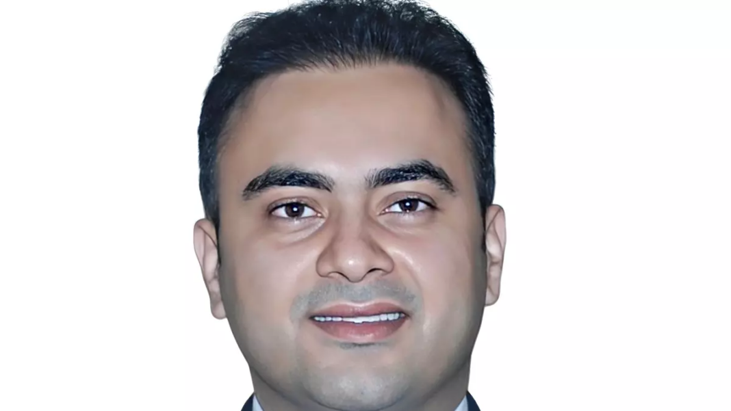 Smiling man in formal attire with white background.