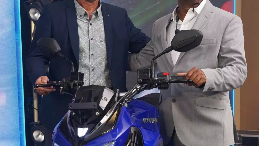 Two men unveiling new motorcycle on stage.