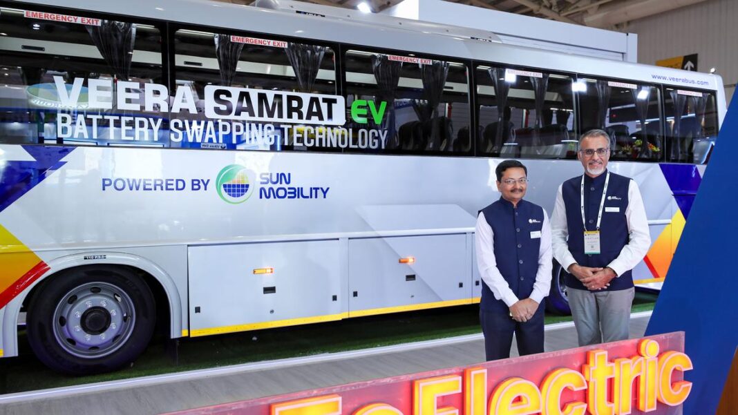 Two men presenting electric bus with battery swapping technology.