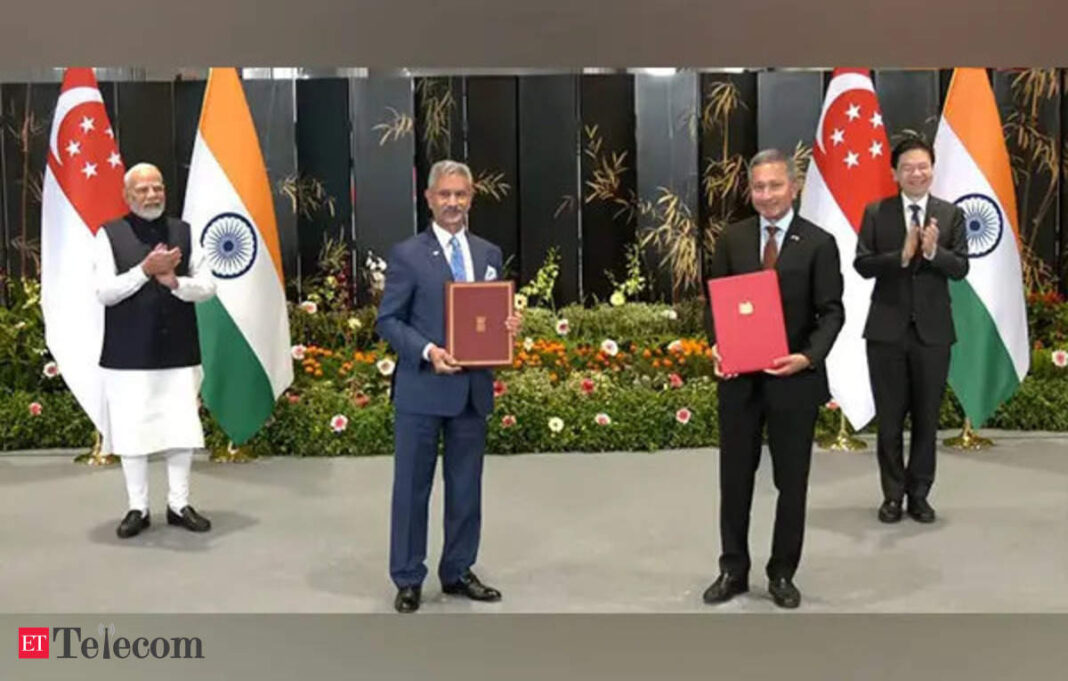 Officials holding agreements, flags of India and Singapore.