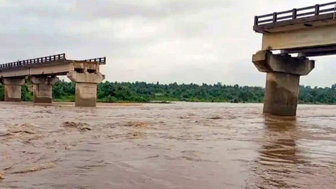 Flooded river under partially collapsed bridge.