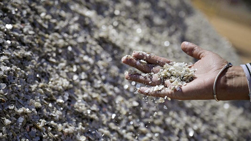 Hand sifting through a pile of raw mineral stones