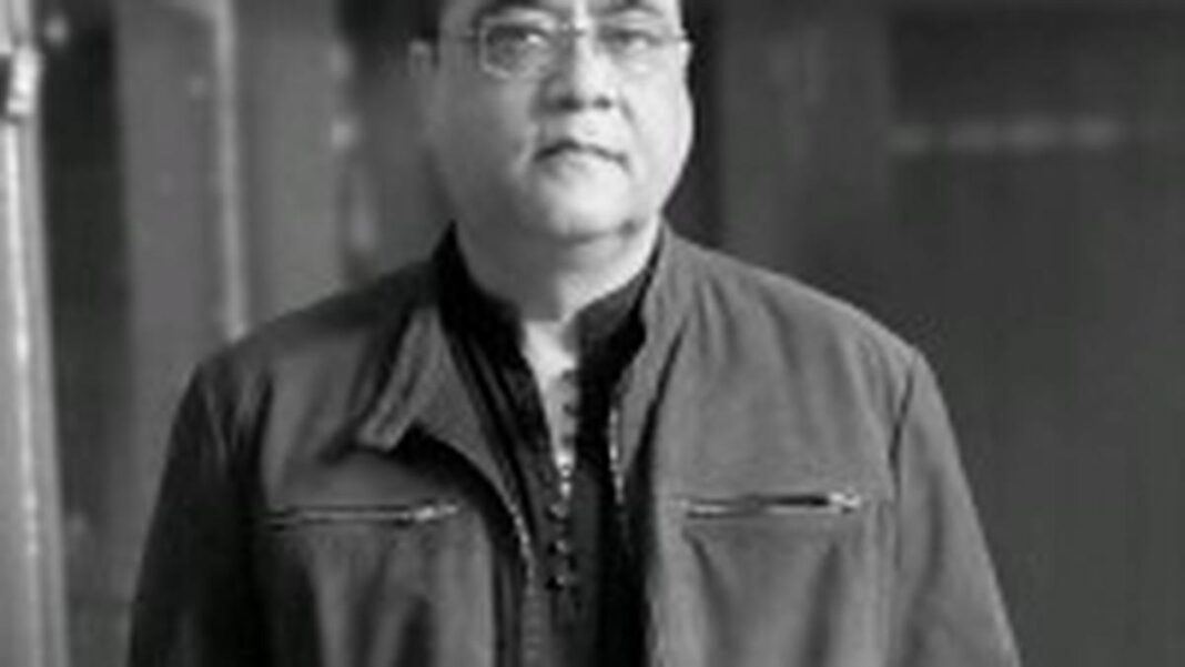 Man in glasses posing in black and white photo.